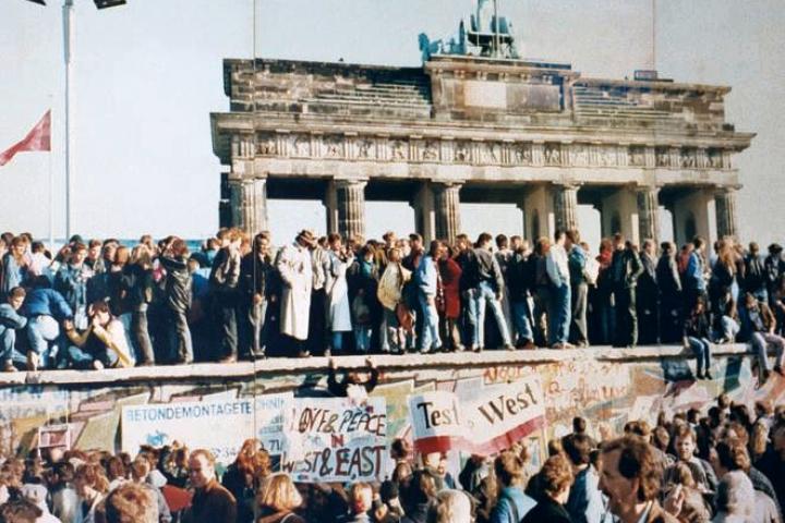 Demonstrators on top of the Berlin Wall on November 9, 1989, the day east and west Berliners broke through the wall. Brandenberg Gate, part of the border of the two parts of the divided city, is in background.